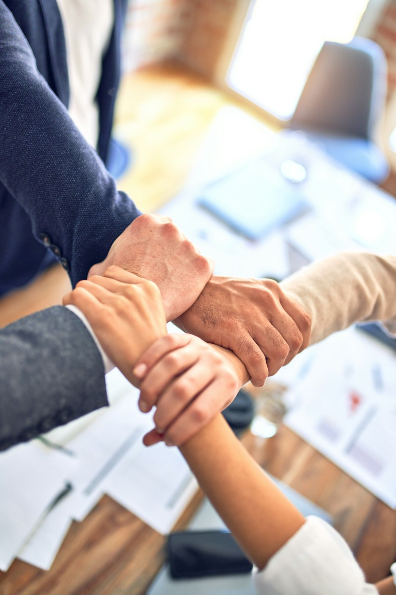 Colleagues joining hands over a table of documents